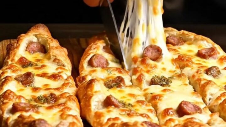 A close-up of a golden brown Turkish pide boat filled with melted cheese and spicy sujuk sausage.