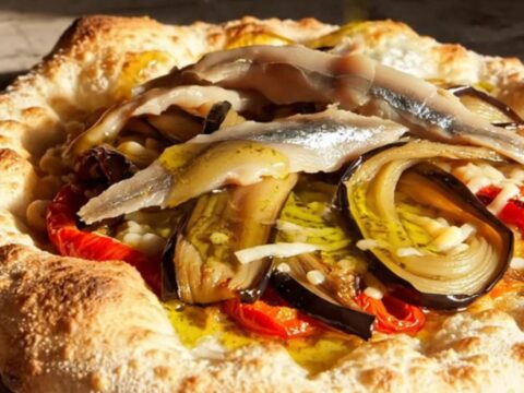 A rustic, crispy Catalan Coca flatbread topped with roasted red peppers, charred eggplant, and anchovies.