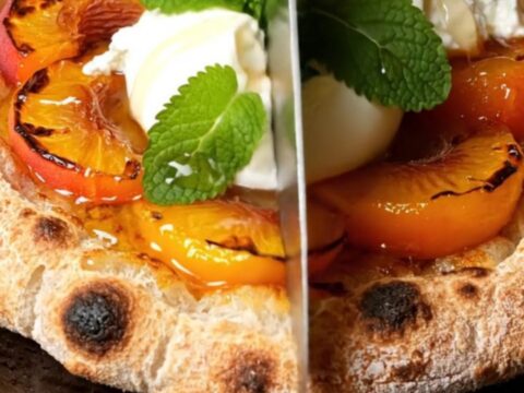 A close-up of a grilled sourdough flatbread topped with charred peach wedges and creamy burrata cheese.