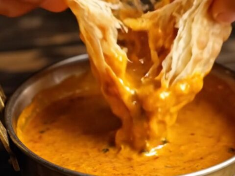 A stack of freshly cooked, golden-brown Malabar parottas with visible flaky layers.