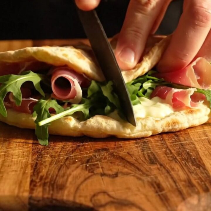 A warm Romagna-style Piadina folded with melted squacquerone cheese, prosciutto crudo, and fresh wild rocket.