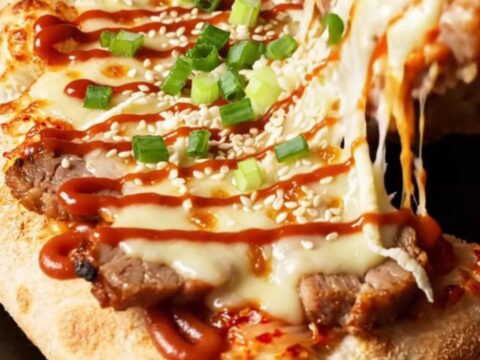A crispy flatbread topped with spicy kimchi, tender pork belly, and melted cheese, finished with a spicy mayo drizzle.