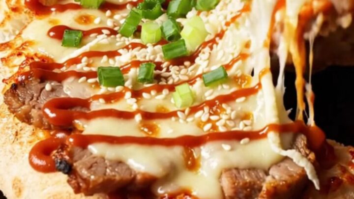 A crispy flatbread topped with spicy kimchi, tender pork belly, and melted cheese, finished with a spicy mayo drizzle.