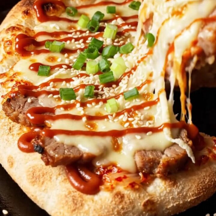 A crispy flatbread topped with spicy kimchi, tender pork belly, and melted cheese, finished with a spicy mayo drizzle.