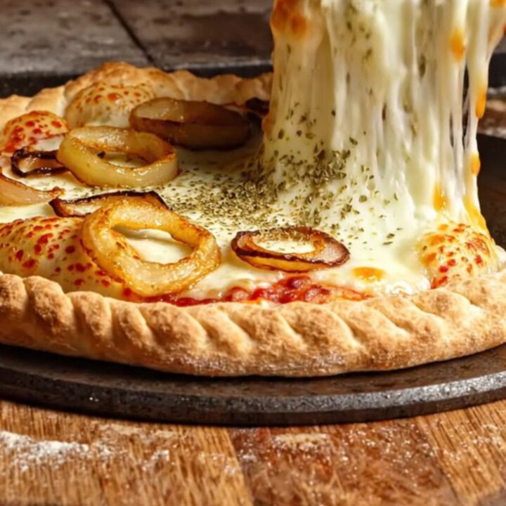 A giant, golden-brown fugazzeta empanada pie cut into wedges, showing a massive pull of melted mozzarella and sweet onions.
