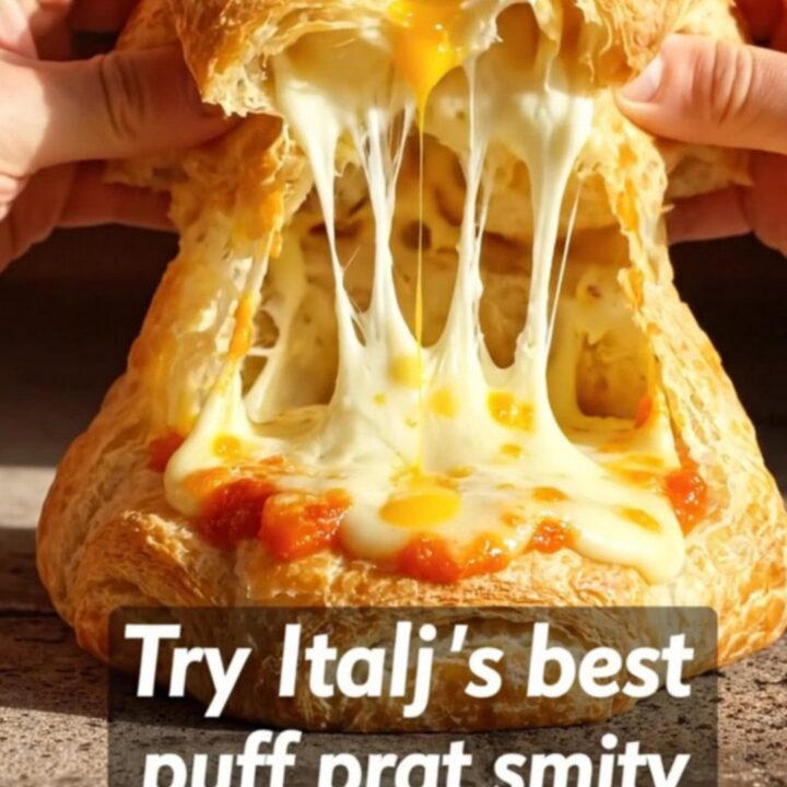 A golden, flaky Rustico Leccese pastry cut in half, revealing a steaming center of béchamel, mozzarella, and tomato.