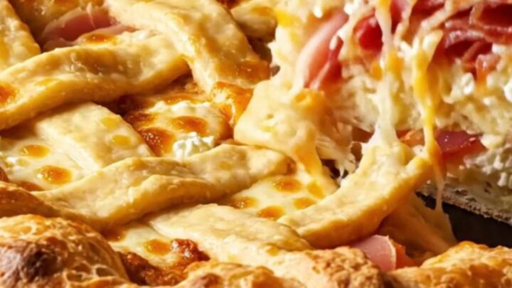 A tall, golden-brown Pizza Rustica pie with a lattice crust, sliced to reveal layers of ricotta, meat, and cheese.