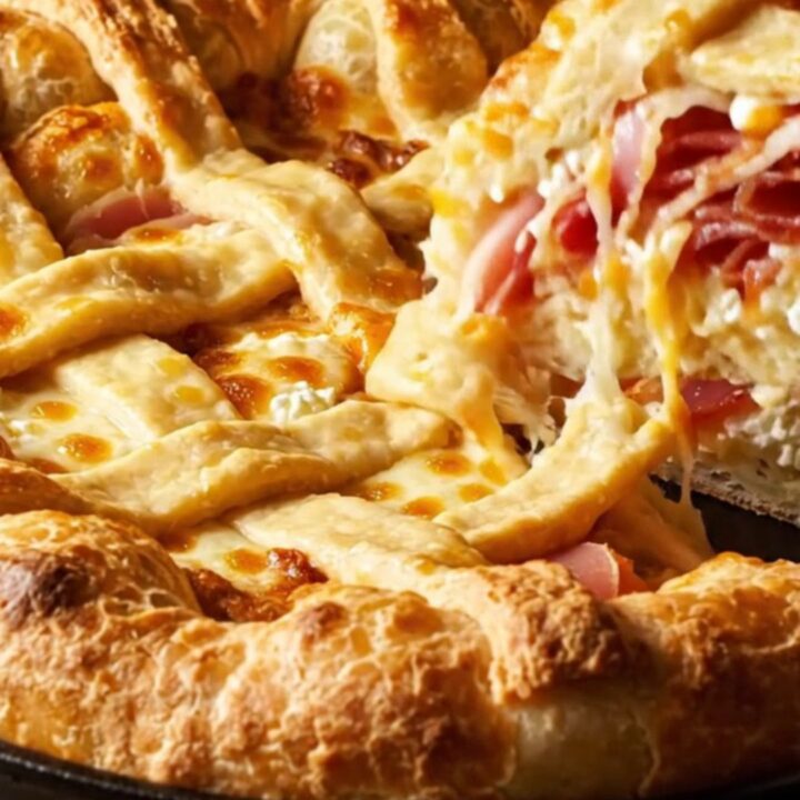 A tall, golden-brown Pizza Rustica pie with a lattice crust, sliced to reveal layers of ricotta, meat, and cheese.