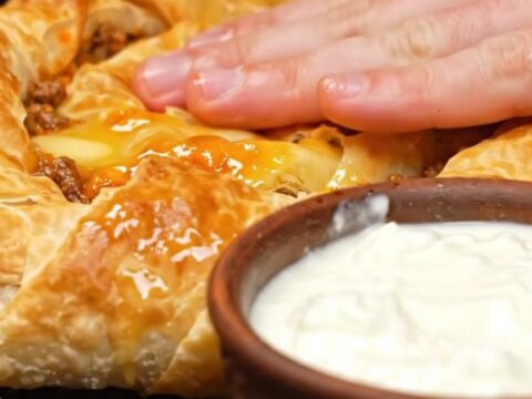A golden, spiraled Bosnian Burek resting in a cast-iron skillet, showing crispy, flaky layers.
