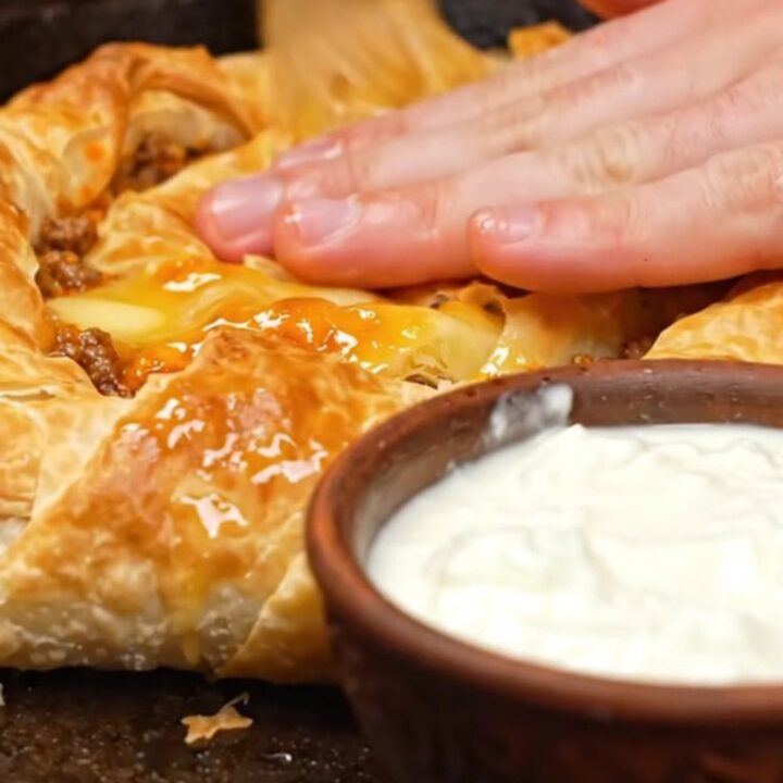 A golden, spiraled Bosnian Burek resting in a cast-iron skillet, showing crispy, flaky layers.