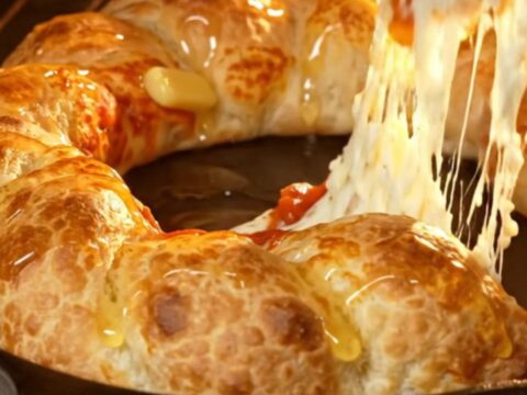 A close-up of a golden, braided stuffed crust pizza ring with a vibrant pepperoni and mozzarella center.