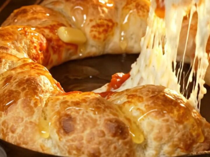 A close-up of a golden, braided stuffed crust pizza ring with a vibrant pepperoni and mozzarella center.