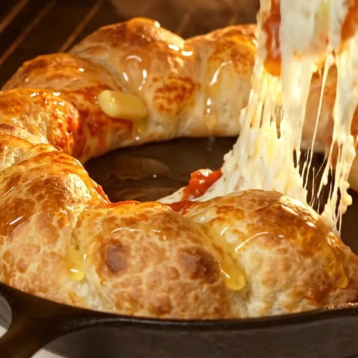 A close-up of a golden, braided stuffed crust pizza ring with a vibrant pepperoni and mozzarella center.
