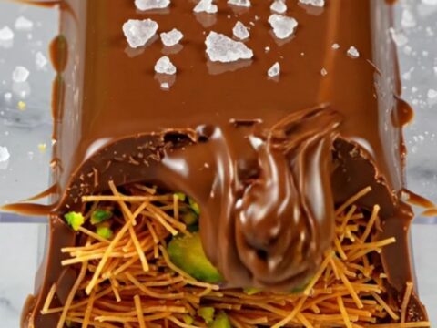 A close-up of a broken Dubai pistachio chocolate bar showing the bright green filling.
