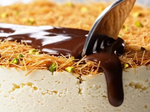 A slice of viral Dubai chocolate cheesecake showing a creamy filling, crunchy pistachio kataifi, and glossy dark chocolate.