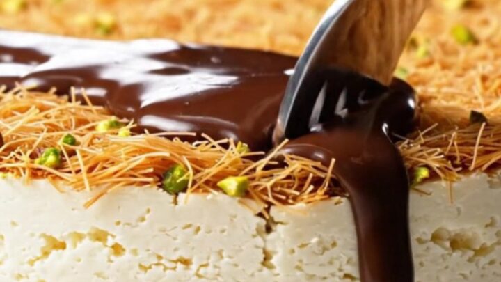 A slice of viral Dubai chocolate cheesecake showing a creamy filling, crunchy pistachio kataifi, and glossy dark chocolate.