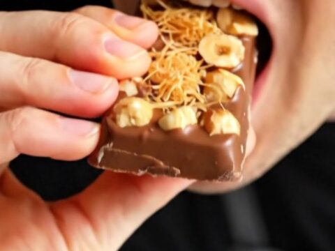 A close-up shot of a broken Gianduja and kataifi chocolate bar showing the creamy hazelnut interior.