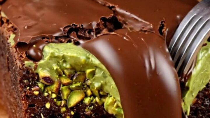 A close-up of a fudgy brownie square topped with a crunchy pistachio kataifi layer and a glossy