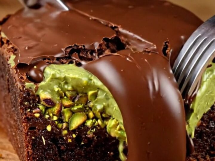 A close-up of a fudgy brownie square topped with a crunchy pistachio kataifi layer and a glossy