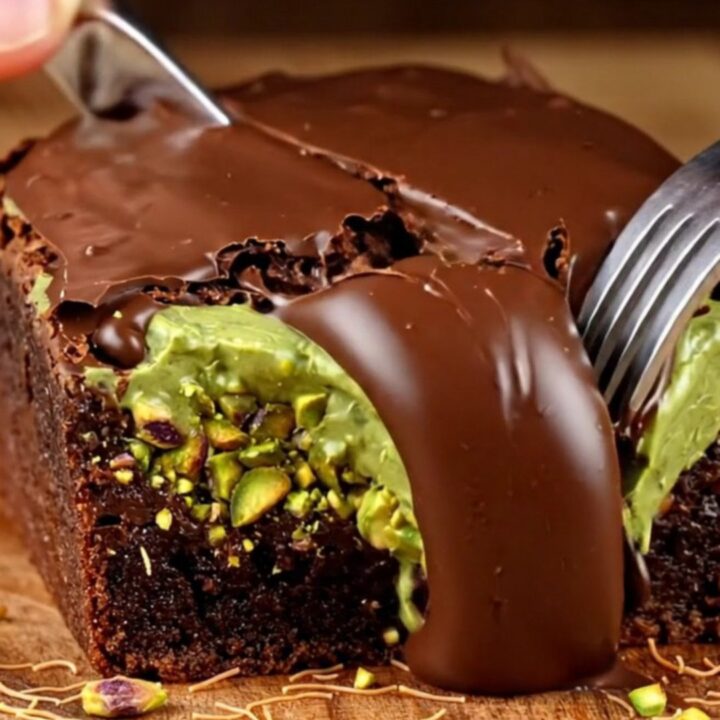 A close-up of a fudgy brownie square topped with a crunchy pistachio kataifi layer and a glossy