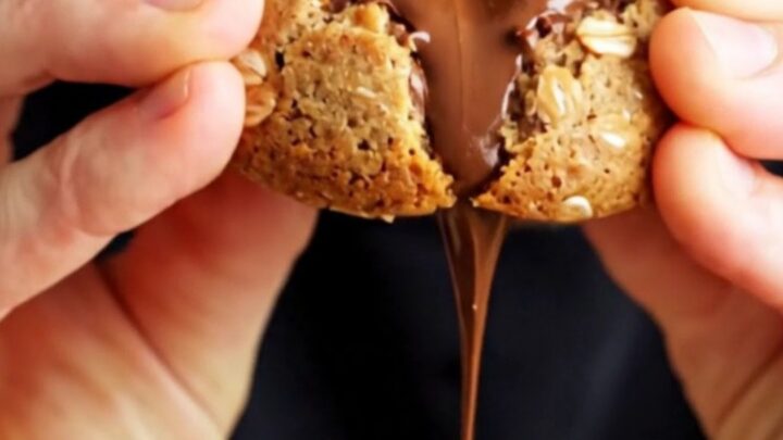 Extreme close-up of a warm monster cookie being pulled apart to reveal a molten peanut butter cup center.