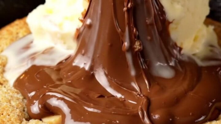 A warm, giant hazelnut skillet cookie in a cast-iron pan with a molten Nutella center.
