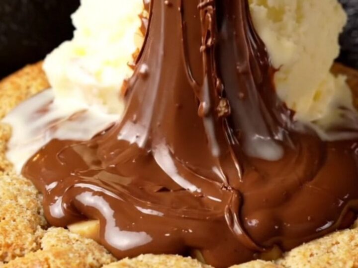 A warm, giant hazelnut skillet cookie in a cast-iron pan with a molten Nutella center.