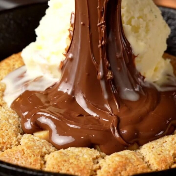 A warm, giant hazelnut skillet cookie in a cast-iron pan with a molten Nutella center.