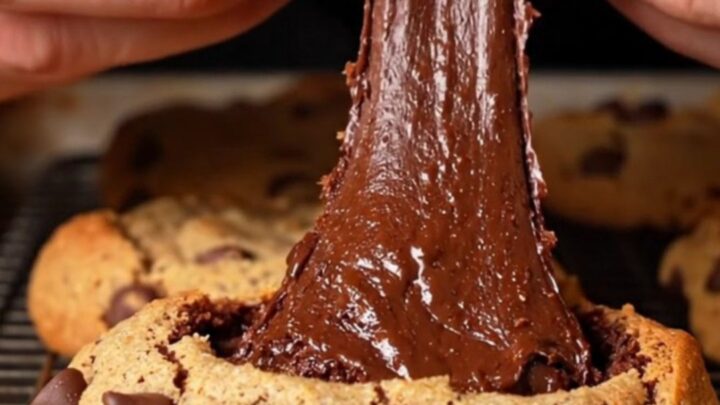 A golden-brown chocolate chip cookie broken in half to reveal a dense, fudgy dark chocolate brownie center.