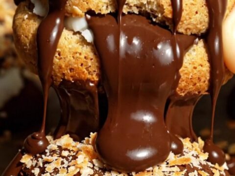 A close-up shot of a dark chocolate cookie broken in half to reveal a sweet, chewy white coconut center.