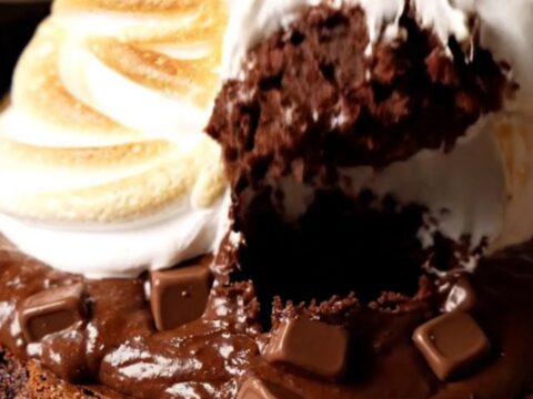 A cast-iron skillet filled with a chocolate brownie topped with toasted marshmallow meringue.
