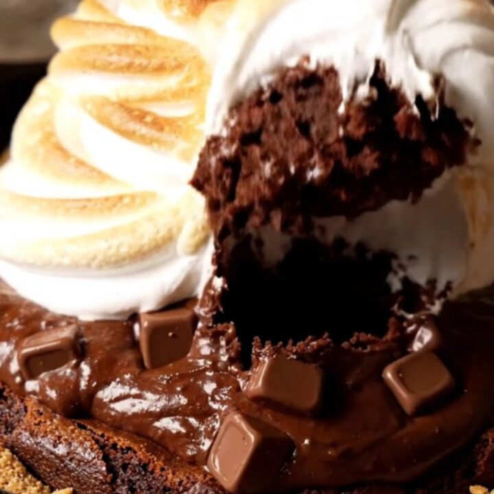 A cast-iron skillet filled with a chocolate brownie topped with toasted marshmallow meringue.