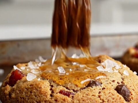 A close-up shot of a warm, broken cookie revealing melted dark chocolate and crispy bacon bits.