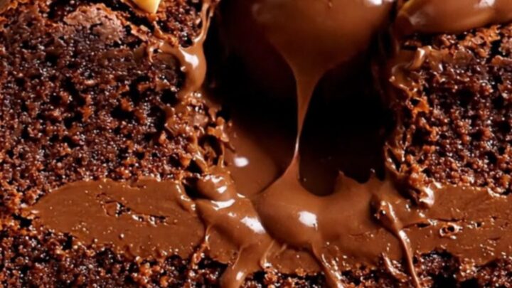 A close-up shot of a Ferrero Rocher stuffed brownie sliced in half, revealing the hazelnut truffle and molten Nutella center.
