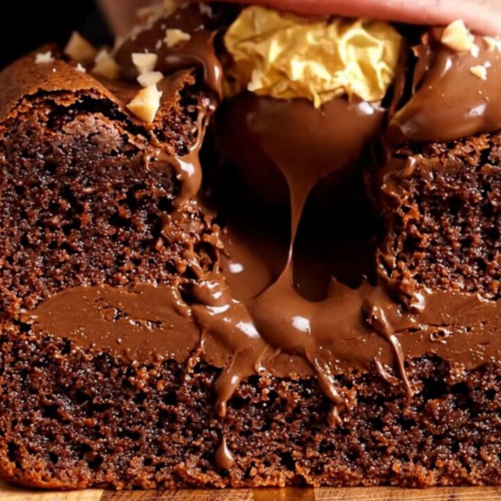 A close-up shot of a Ferrero Rocher stuffed brownie sliced in half, revealing the hazelnut truffle and molten Nutella center.