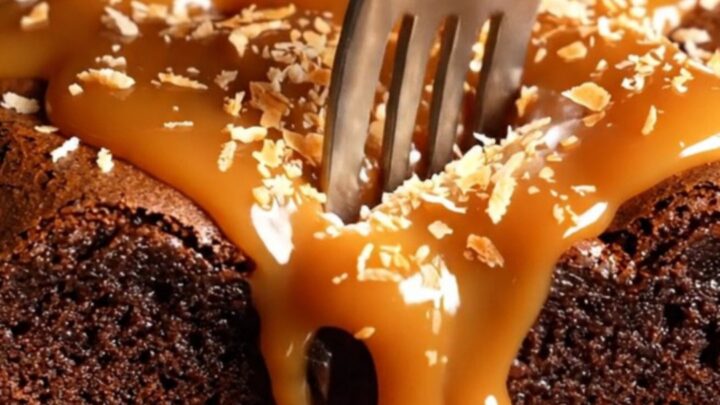 Extreme close-up of a dense dark chocolate brownie being pulled apart to reveal caramel swirls.