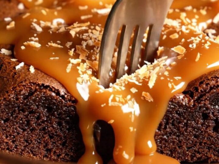 Extreme close-up of a dense dark chocolate brownie being pulled apart to reveal caramel swirls.