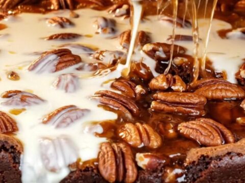 A close-up of a decadent brookie with a dark brownie base and a gooey, glossy bourbon pecan pie topping.
