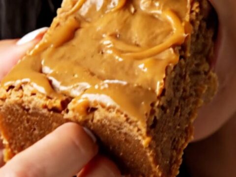A stack of thick, golden-brown blondies with a shiny, crackly top, showing melted butterscotch and bits of toffee inside.