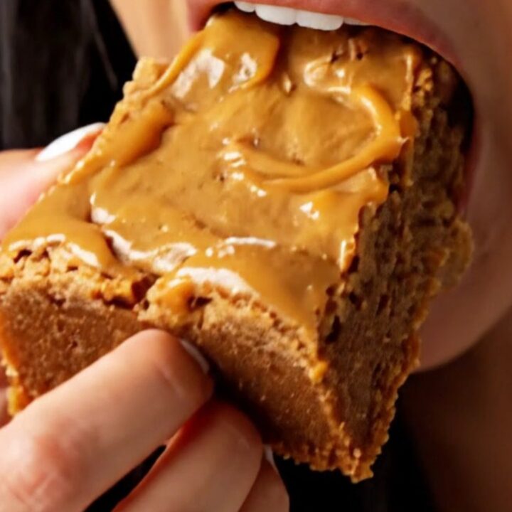 A stack of thick, golden-brown blondies with a shiny, crackly top, showing melted butterscotch and bits of toffee inside.