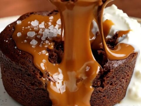 A warm, decadent molten chocolate cake broken open to reveal a flowing salted caramel core on a plate.