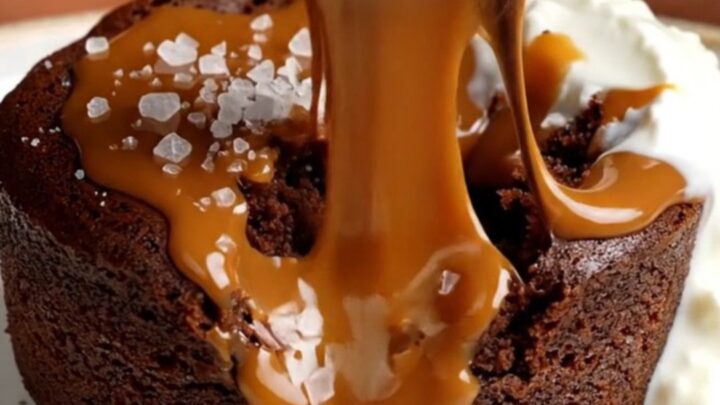 A warm, decadent molten chocolate cake broken open to reveal a flowing salted caramel core on a plate.