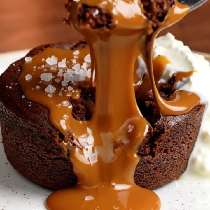 A warm, decadent molten chocolate cake broken open to reveal a flowing salted caramel core on a plate.
