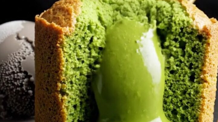 A close-up shot of a jade-green matcha molten lava cake with a flowing liquid center on a black stone table.
