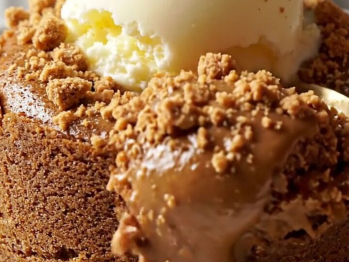 A close-up of a warm Biscoff lava cake with a molten center pouring out onto a plate.