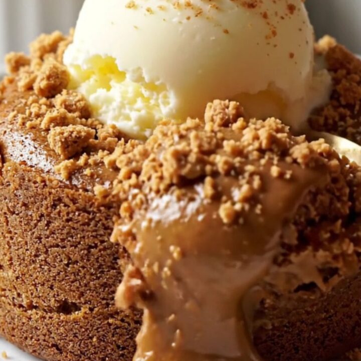 A close-up of a warm Biscoff lava cake with a molten center pouring out onto a plate.