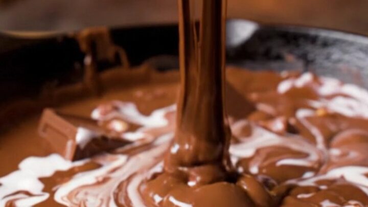 A cast-iron skillet filled with a molten triple chocolate fondue with marshmallow swirls and hazelnuts.