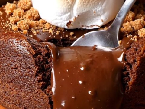A close-up of a Mexican spiced chocolate lava cake with a molten center spilling out after being cut with a spoon.
