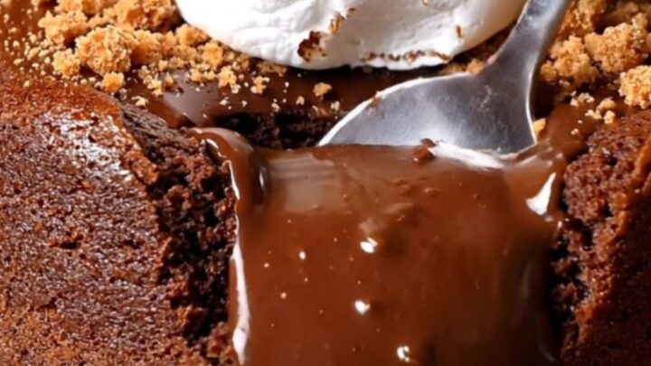 A close-up of a Mexican spiced chocolate lava cake with a molten center spilling out after being cut with a spoon.