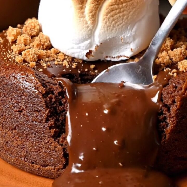 A close-up of a Mexican spiced chocolate lava cake with a molten center spilling out after being cut with a spoon.